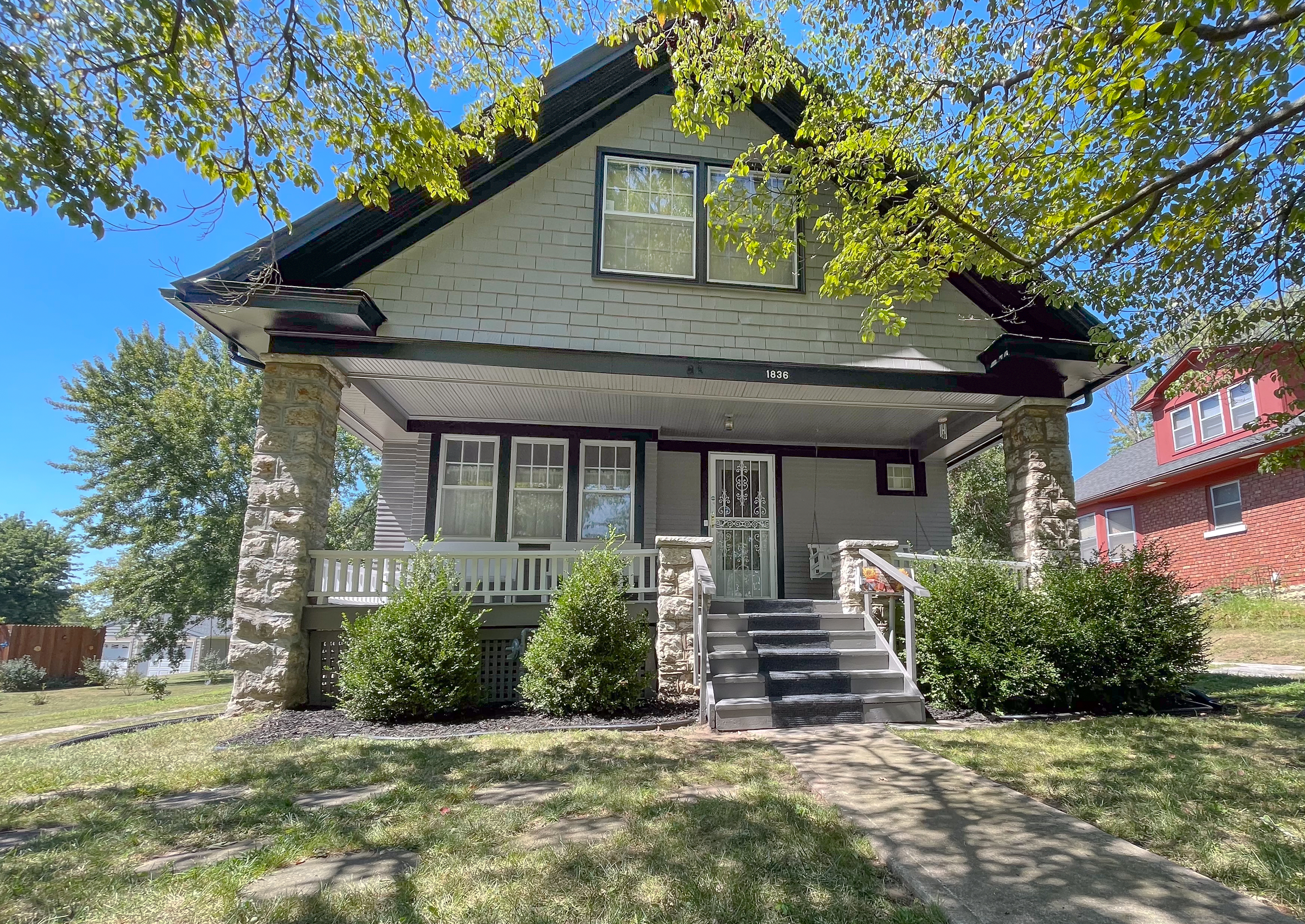 Historic craftsman house exterior with shingle siding and heavy stone porch columns in Independence, MO by Red Letter Painting