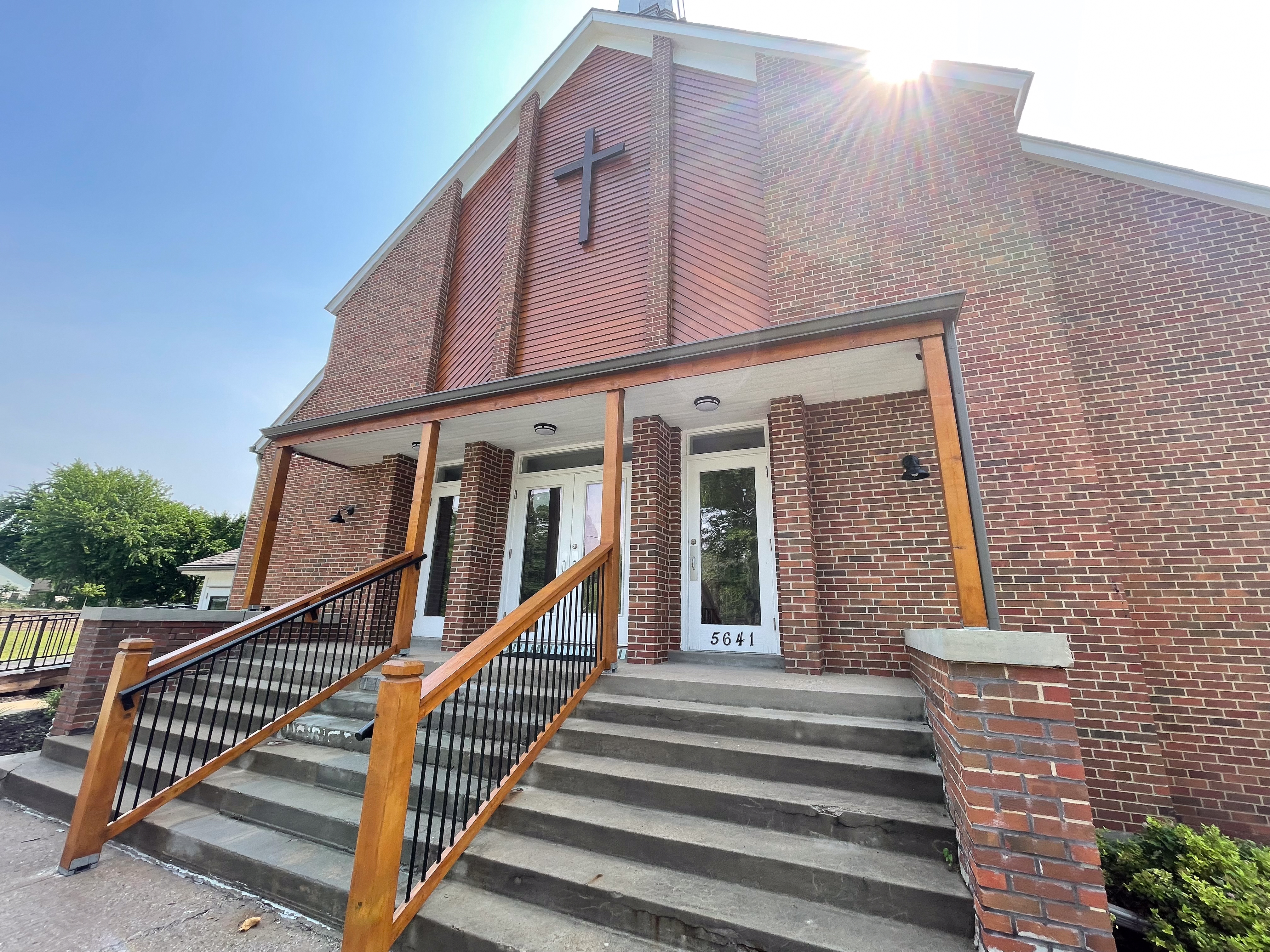 Church building exterior entry with stained wood pillars and handrails in Overland Park, KS by Red Letter Painting