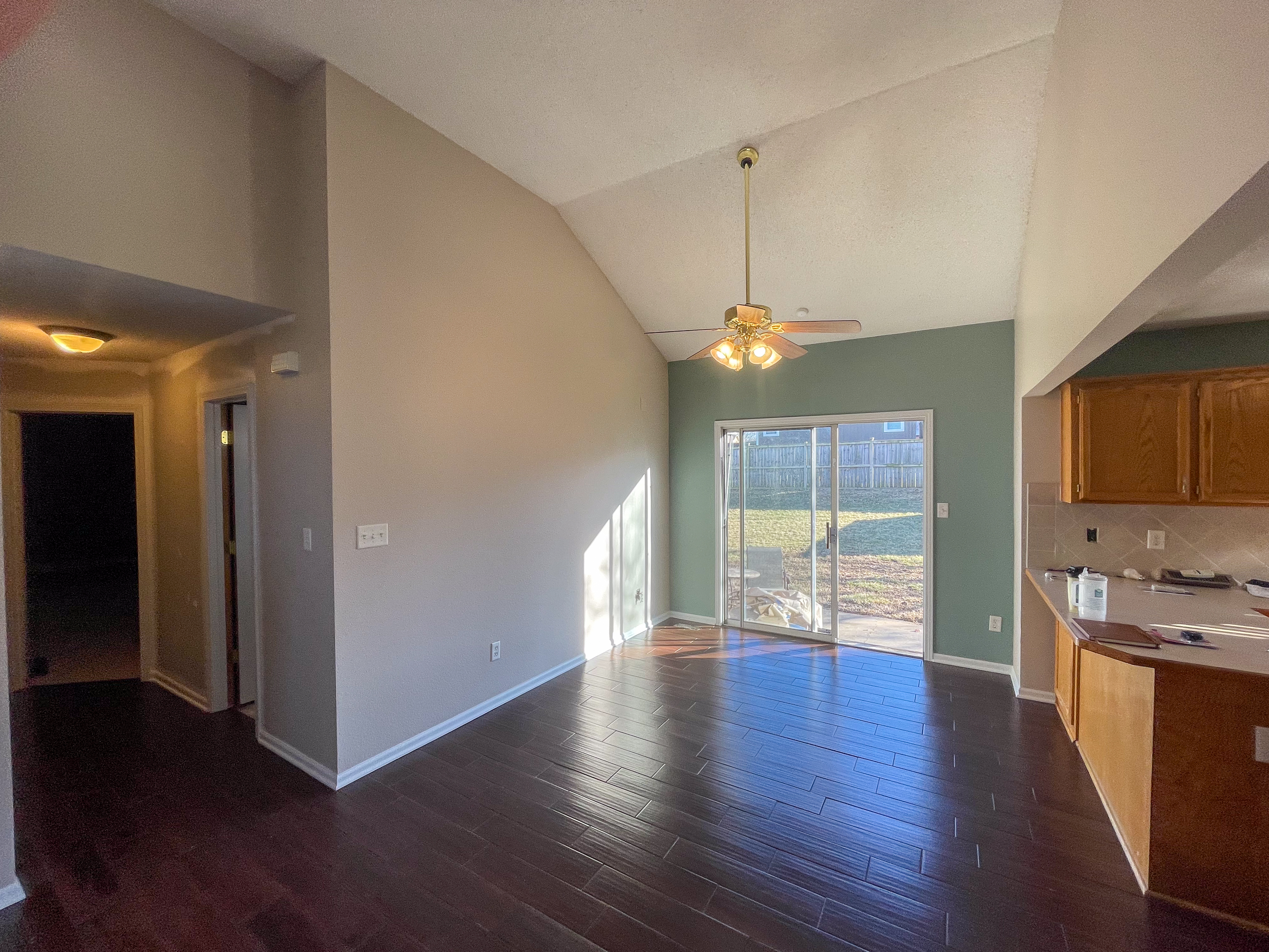 Open-concept dining and living room with sage green accent wall in Independence, MO by Red Letter Painting